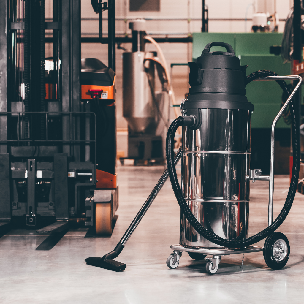 Industrial shop vac next to a forklift in a busy warehouse.