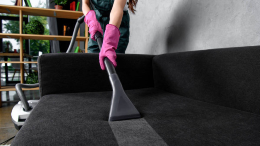 Residential cleaning service vacuuming upholstery in a home